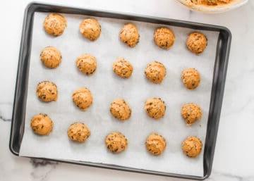 Kürbis-Schoko-Cookie-Teigkugeln, sauber auf einem mit Backpapier ausgelegten Backblech angeordnet.