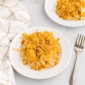 Beerdigungskartoffeln 2 Funeral Potatoes auf einem weißen Teller angerichtet, daneben eine Gabel.