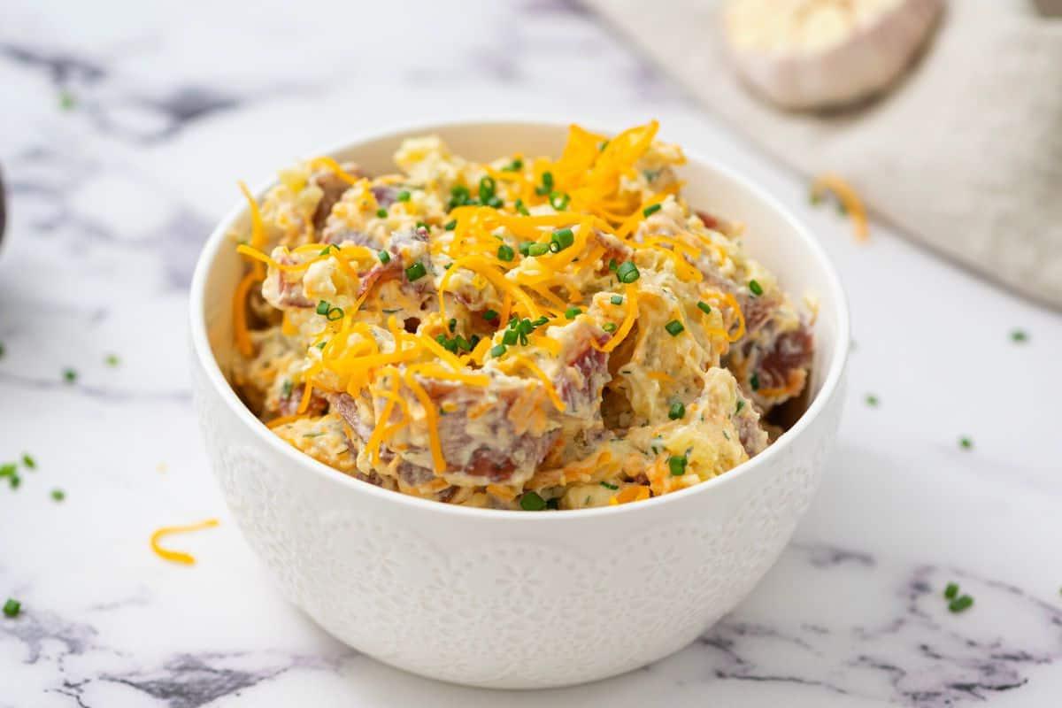 Bacon Ranch Kartoffelsalat garniert mit Käse, Schnittlauch und Speck.