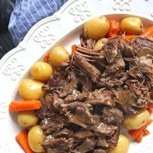 Instant Pot Schmorbraten in Scheiben auf einer weißen Platte mit Karotten und Kartoffeln.