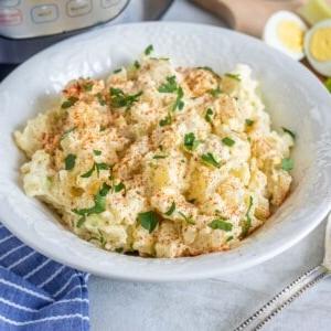 Schüssel mit Instant Pot Kartoffelsalat mit Instant Pot im Hintergrund.
