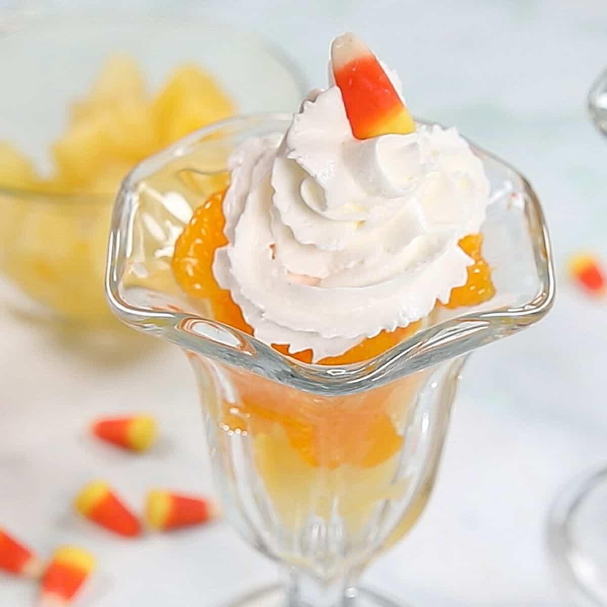 Geschichtetes Obst in einem Glasparfait, gekrönt mit einem Candy Corn.