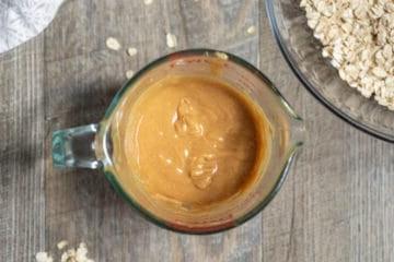 Glasmessbecher mit erhitzter, vermischter Erdnussbutter und Honig.