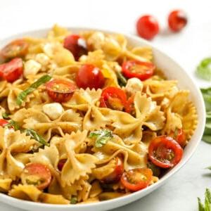 Nahaufnahme einer Schüssel Nudelsalat mit Tomaten und Basilikum.