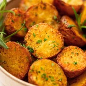 Geröstete rote Kartoffeln in einer großen Schüssel, gewürzt mit Salz, Pfeffer und Rosmarin und garniert mit frischer Petersilie.