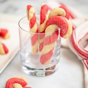 Zuckerstangen-Plätzchen, die an einem Trinkglas hängen.