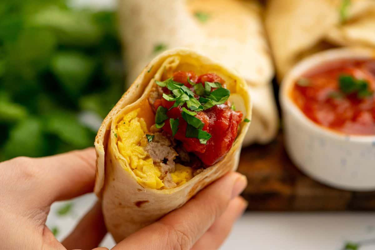 Aufgeschnittener Frühstücks-Burrito, serviert mit frischer Salsa.
