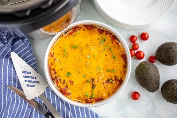 Gekochte Instant Pot Mexican Lasagne in der Form neben dem Instant Pot und Tellern.