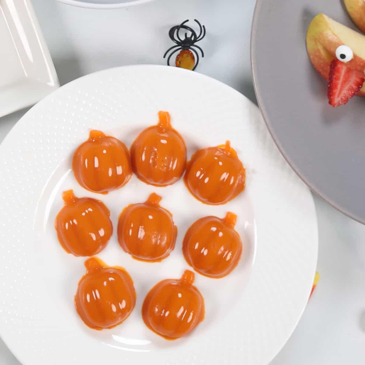 Kürbisförmige Gummibärchen auf einem weißen Teller.