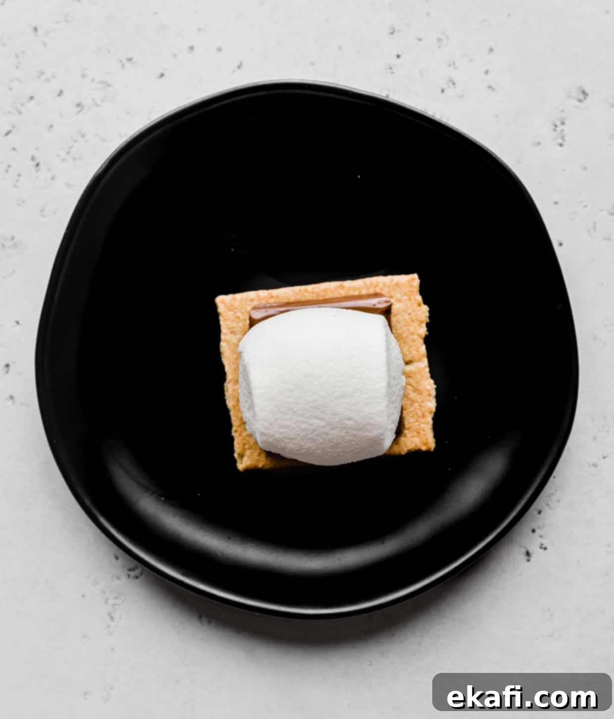 Σμόρες στο φούρνο μικροκυμάτων 5 Ένα marshmallow πάνω από ένα τετράγωνο σοκολάτας που βρίσκεται πάνω σε ένα μπισκότο graham.
