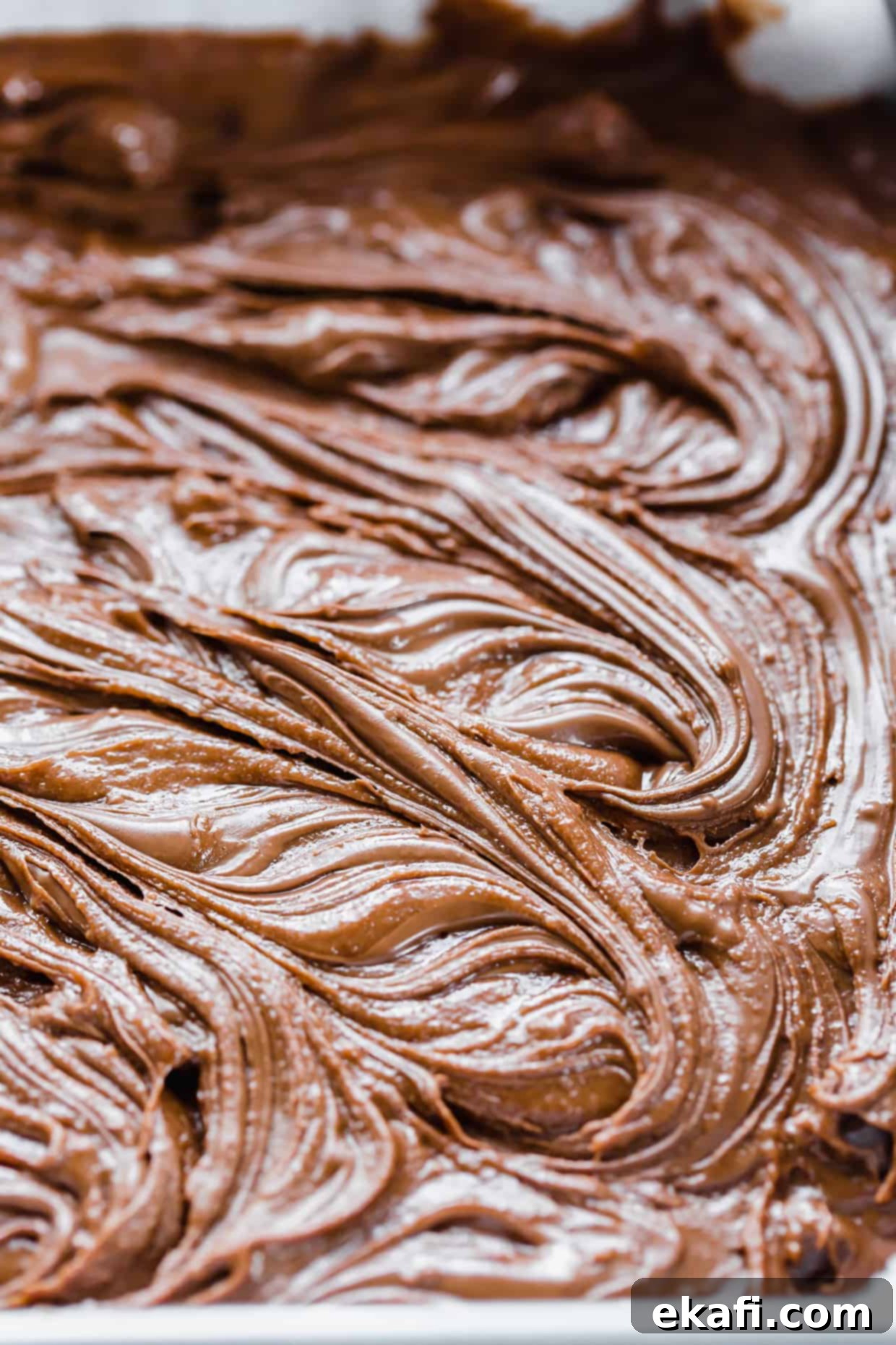 Ζύμη Nutella Brownies με κουταλιές Nutella να ανακατεύονται στη μη ψημένη ζύμη.