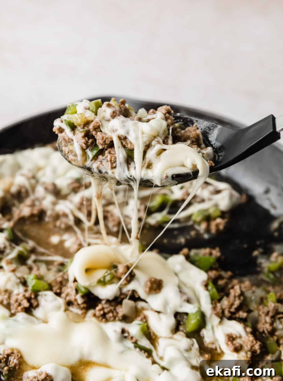 Φιλαδέλφειας Τυρόστεικ Σλόπι Τζο 8 A large black spoon scooping up Philly Cheesesteak Sloppy Joes mixture from a skillet.