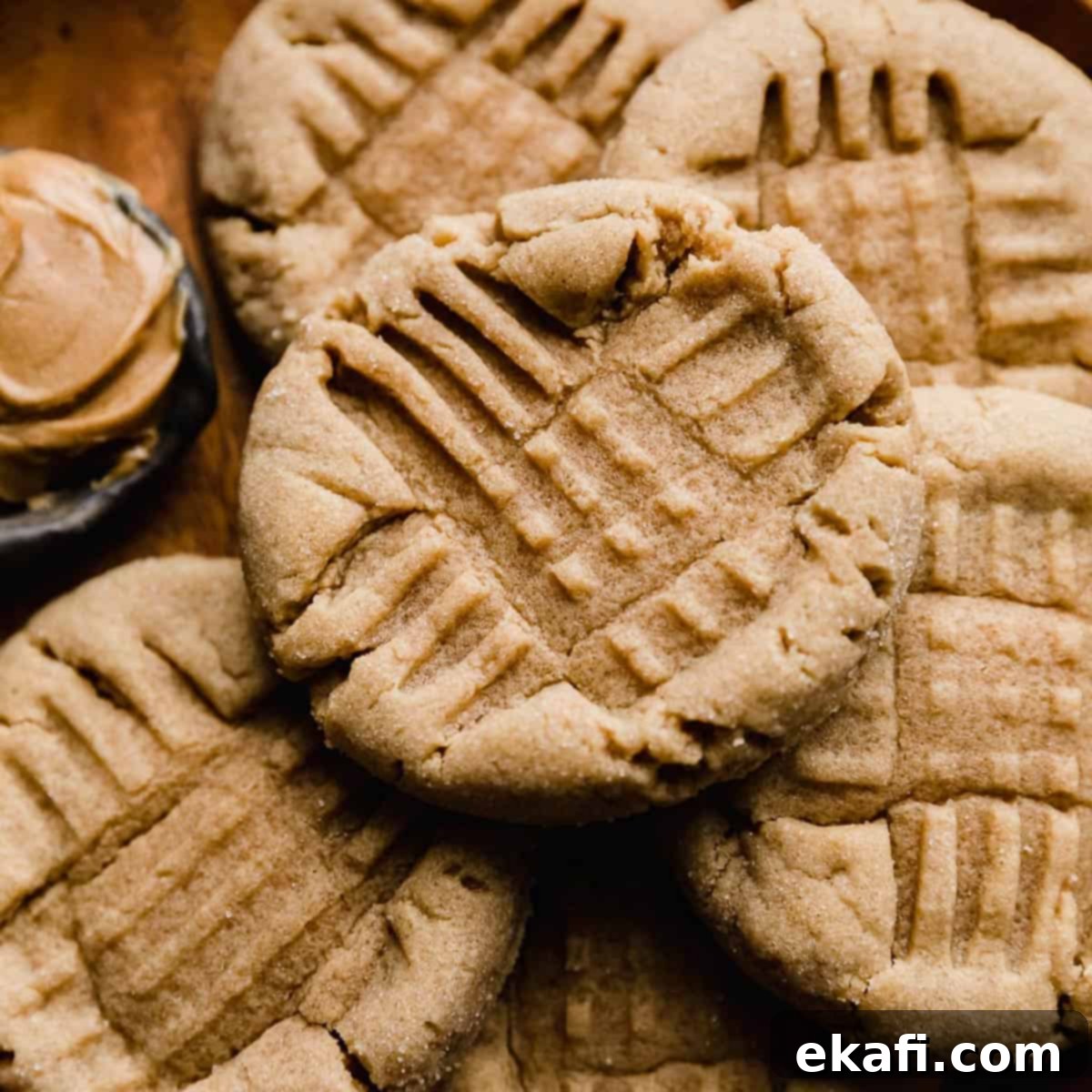 Κοντινή φωτογραφία ενός κλασικού Peanut Butter Cookie με σταυρωτά σημάδια από πιρούνι στην κορυφή του μπισκότου.