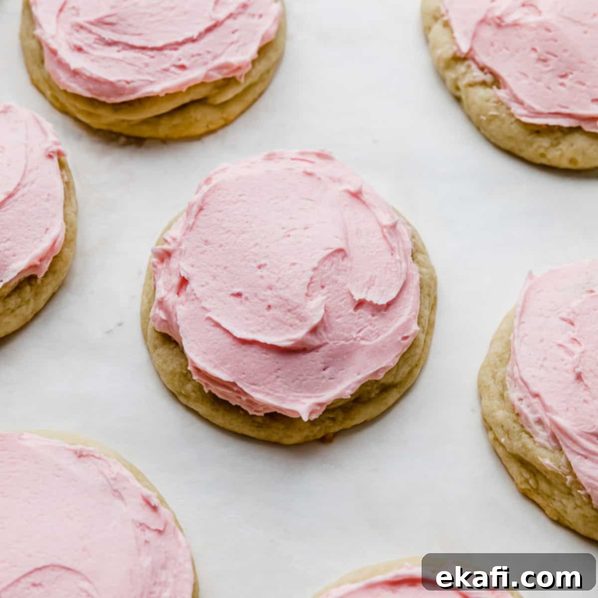 Ένα αντιγραφές crumbl sugar cookie με ροζ γλάσο σε λευκό φόντο.