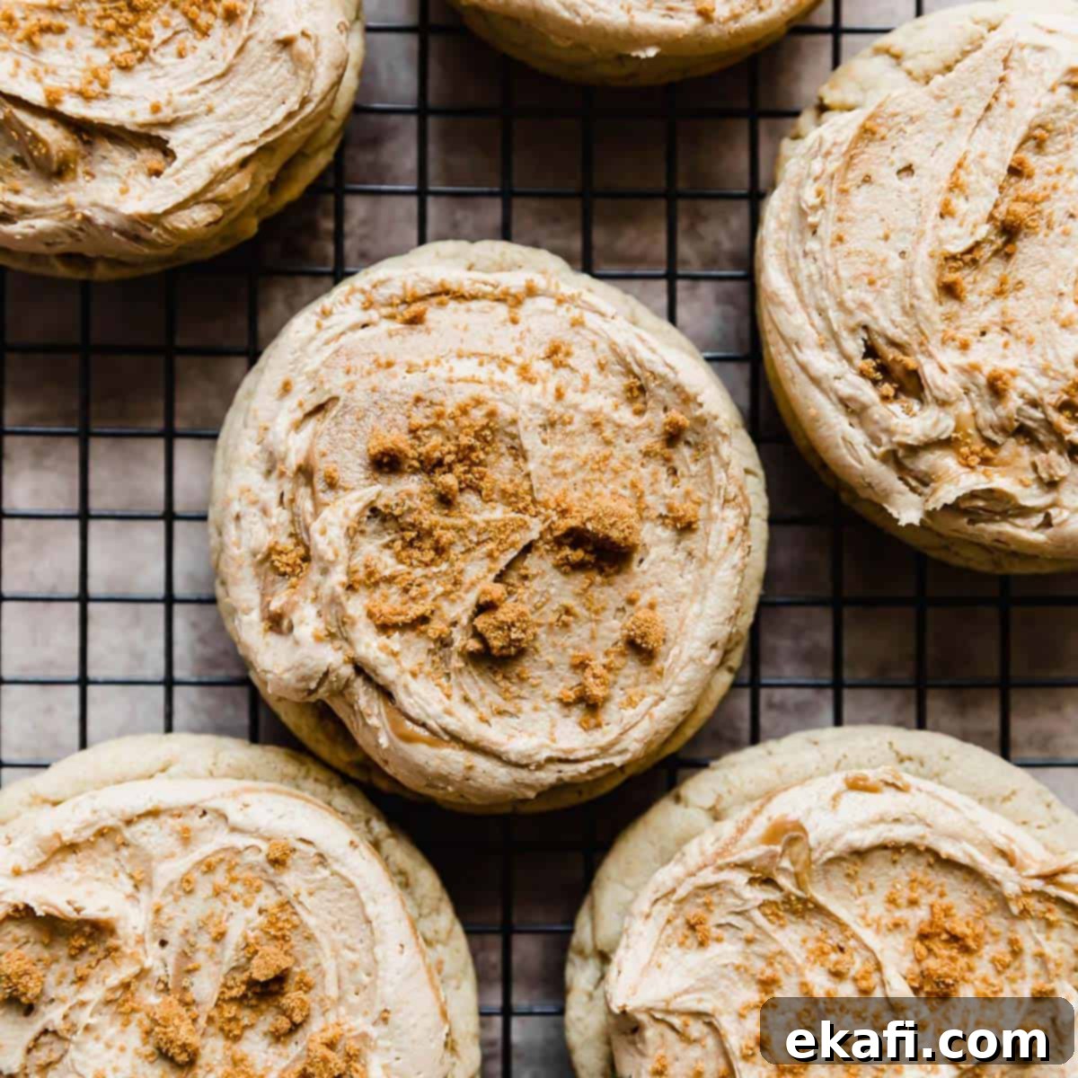 Ένα Crumbl Cookie Butter Cookie με γλάσο και θρυμματισμένα ψίχουλα μπισκότων Biscoff σε μαύρη σχάρα ψύξης.