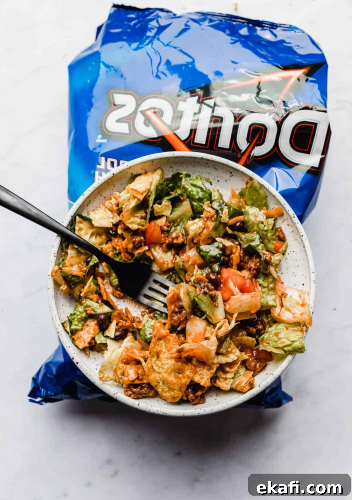 Δωρίτος Τάκο Σαλάτα 2 Σαλάτα Τάκο με Doritos σε λευκό πιάτο που κάθεται πάνω σε μπλε σακούλα με Doritos Cool Ranch.