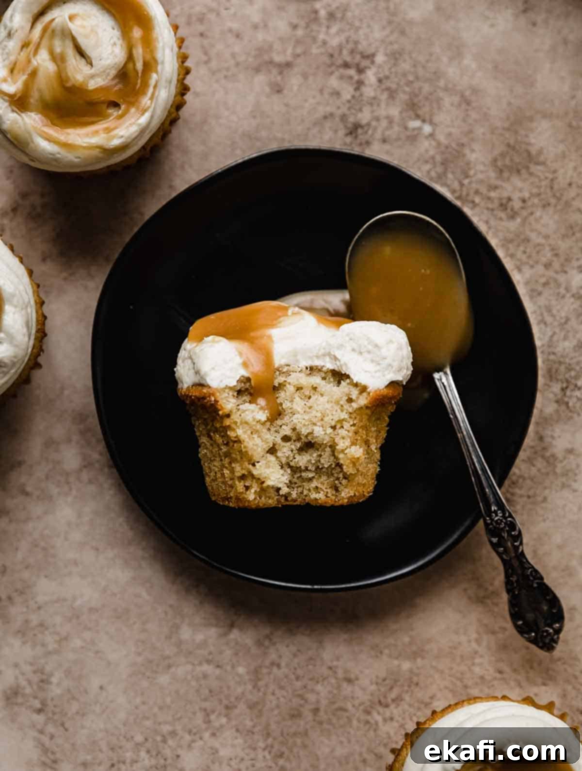 Καπκέικ Καραμέλας Βουτύρου 7 Ένα Cupcake Butterscotch σε μαύρο πιάτο με μια δαγκωματιά από το cupcake.