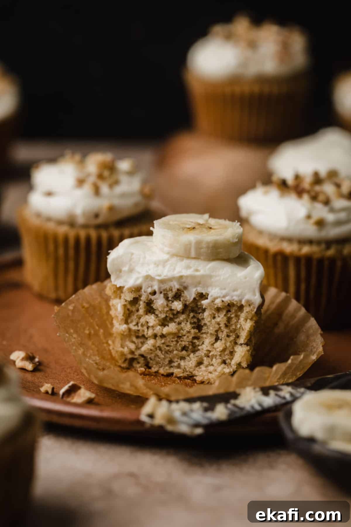 Συνταγή για Κάπκεϊκς Μπανάνας 6 Ένα Cupcake μπανάνας κομμένο στη μέση, που δείχνει πόσο αφράτο είναι, και γαρνιρισμένο με γλάσο τυριού κρέμας.