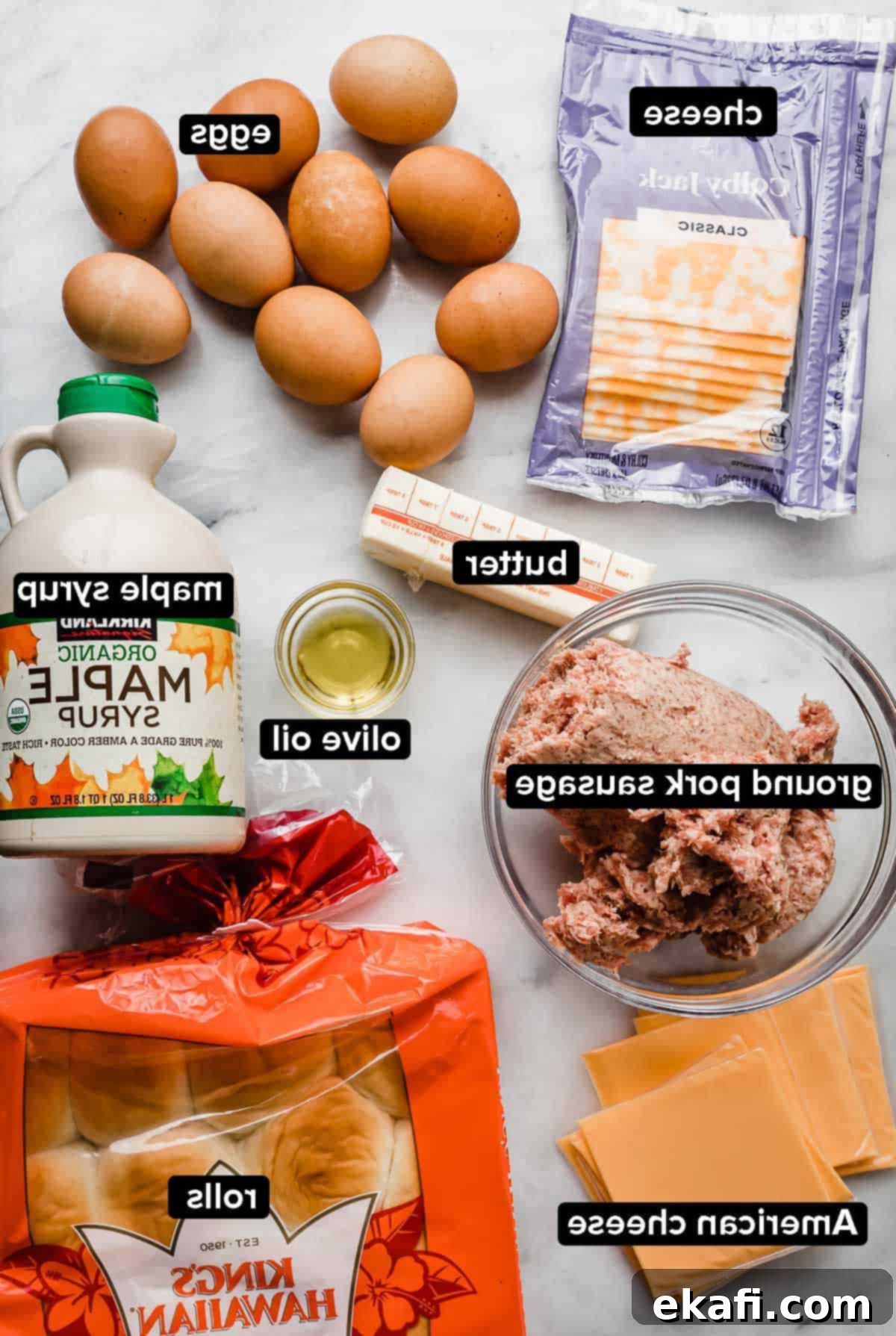 Μίνι Σάντουιτς Πρωινού 3 Συστατικά για Hawaiian Roll Breakfast Sliders σε λευκή μαρμάρινη επιφάνεια: λουκάνικο, τυρί, αυγά, σιρόπι σφενδάμου, βούτυρο.