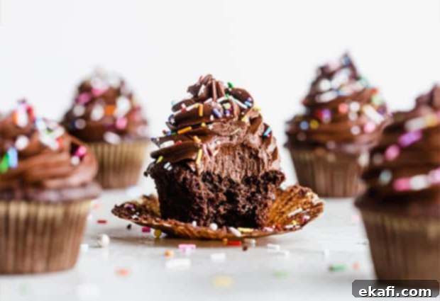 Το καλύτερο σοκολατένιο cupcake με σοκολατένια βουτυρόκρεμα και πολύχρωμη τρούφα, με ένα μεγάλο δάγκωμα από το cupcake.