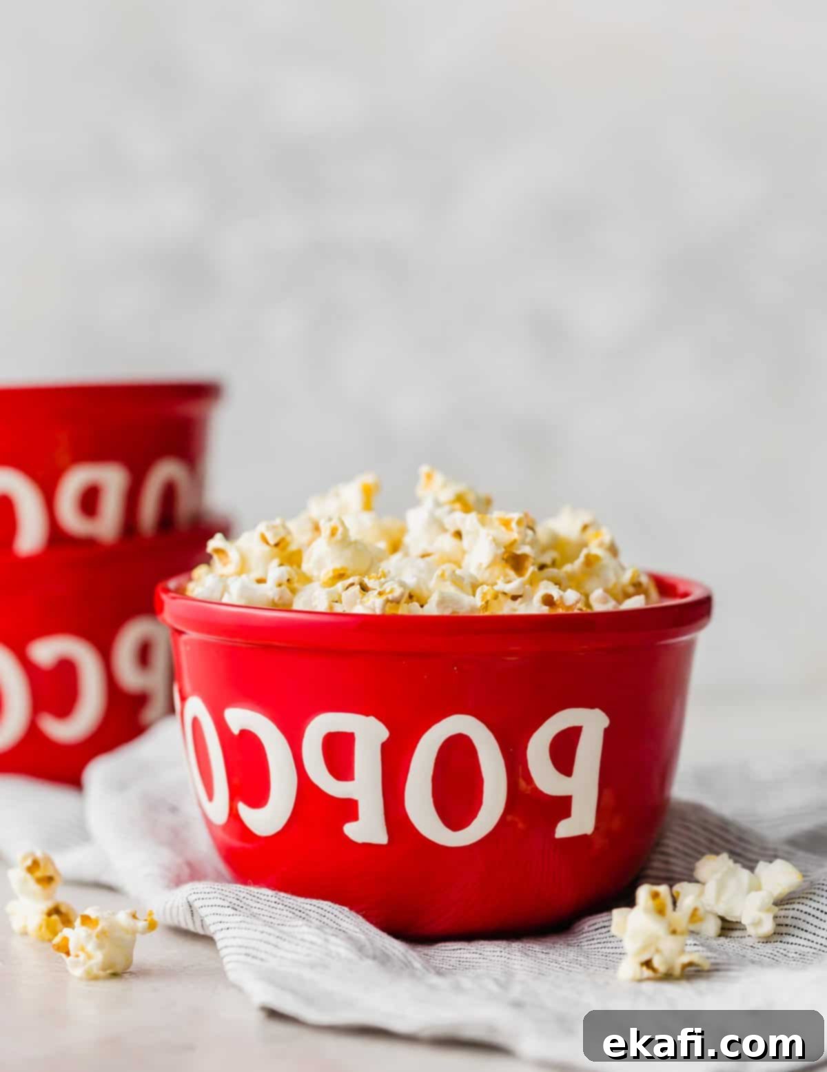 Ένα κόκκινο μπολ με τη λέξη "popcorn" πάνω του, με Ποπ κορν κινηματογράφου μέσα στο μπολ.