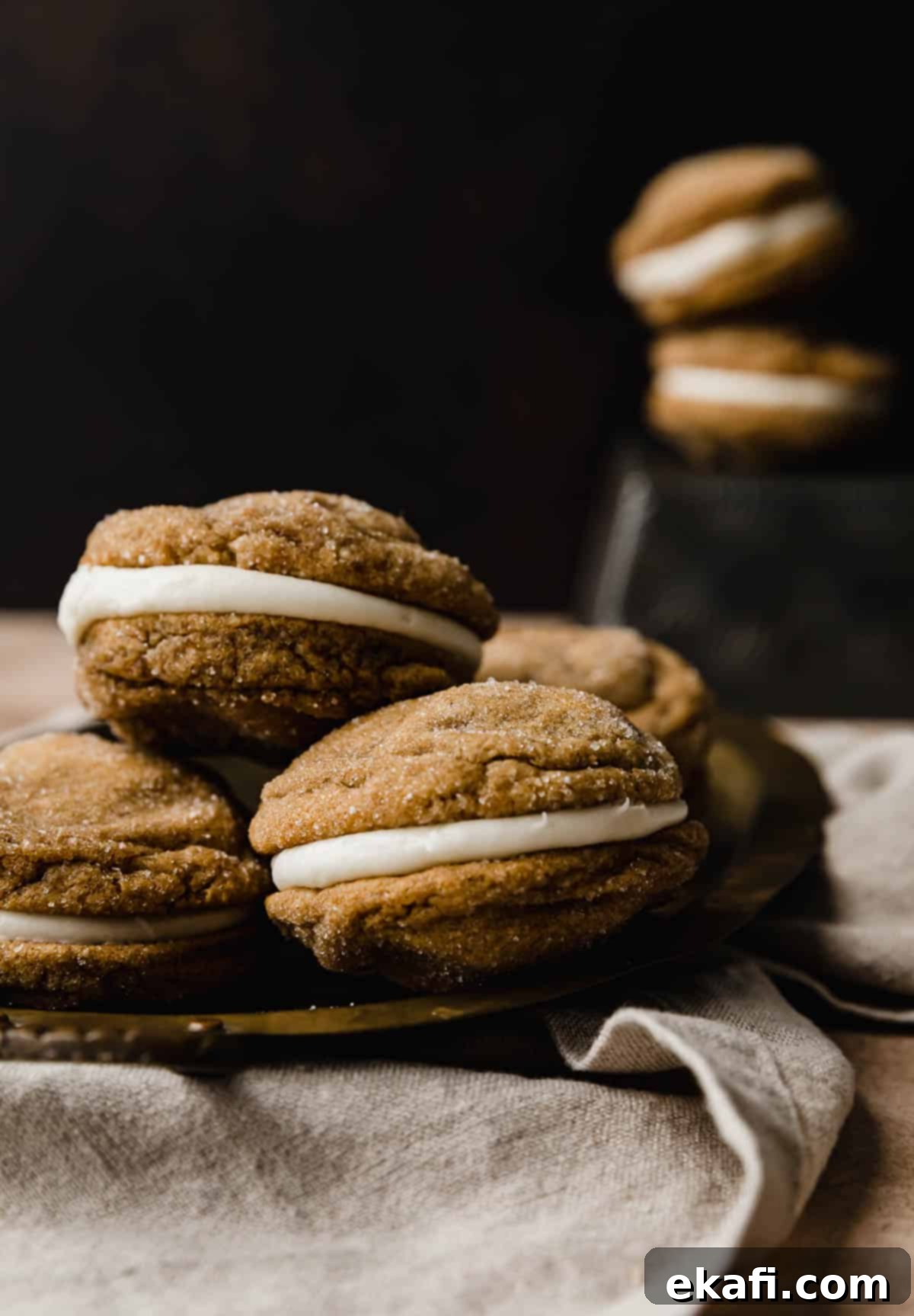 Μπισκότα Σάντουιτς Τζίντζερμπρεντ 7 Gingerbread Whoopie pies με γέμιση κρέμας τυριού, στοιβαγμένα σε ένα μπρονζέ πιάτο σε καφέ φόντο.