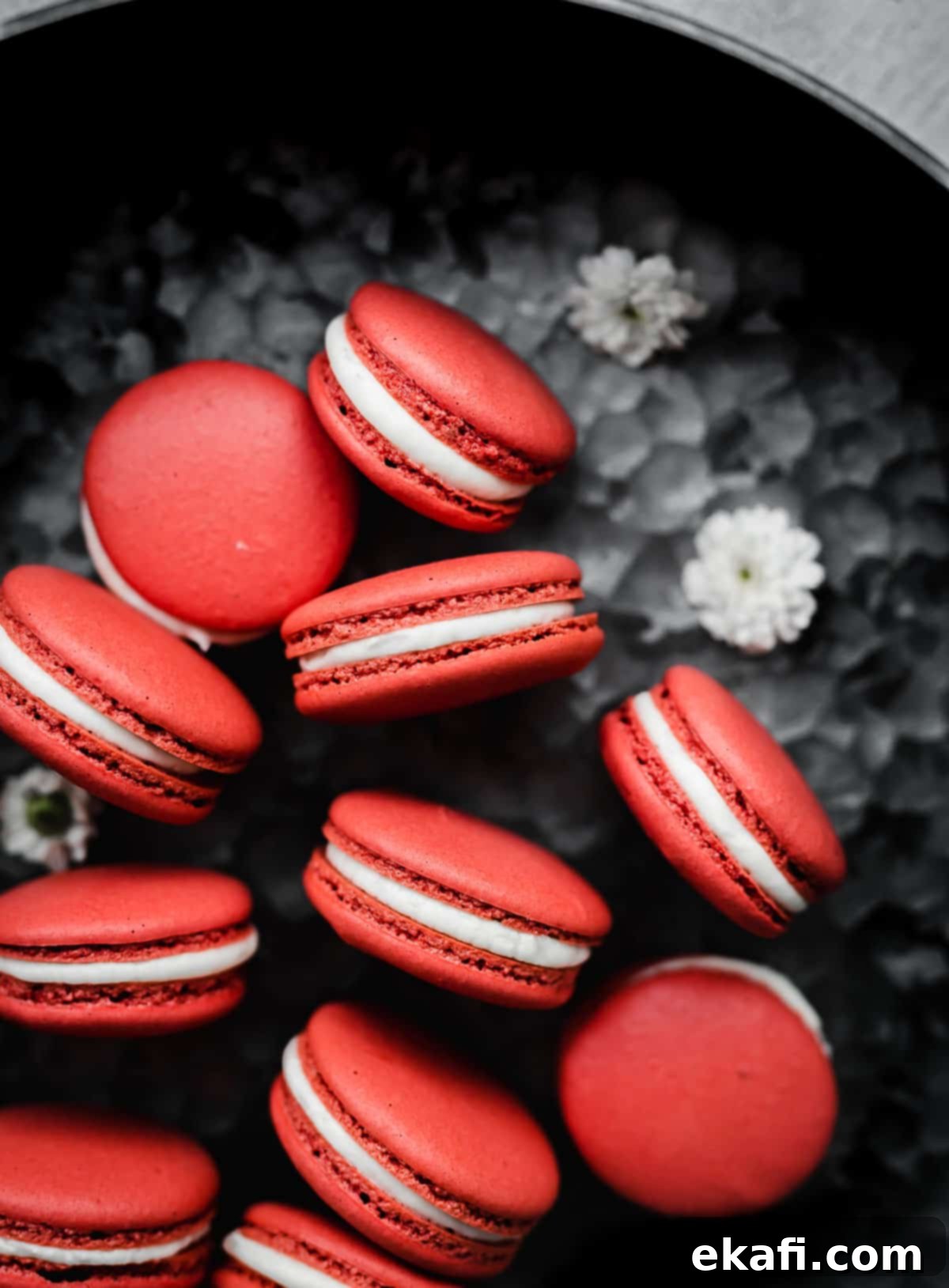 Μακαρόν Κόκκινο Βελούδο 2 Red Velvet Macarons filled with a white frosting, on a gray background.
