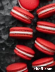Μακαρόν Κόκκινο Βελούδο 11 Red Velvet Macarons filled with a cream cheese frosting on a gray metal background.