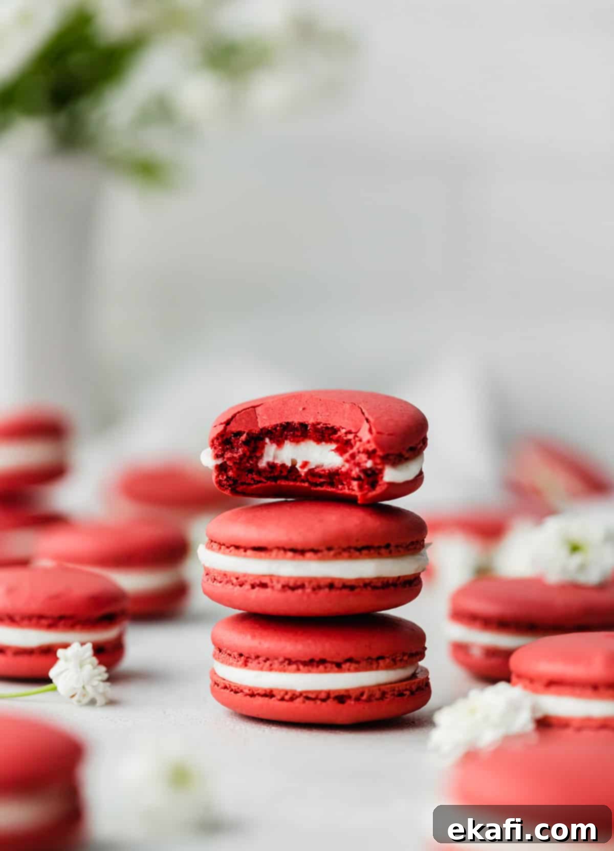 Μακαρόν Κόκκινο Βελούδο 9 A white frosting filled Red Velvet Macaron with a bite taken out of it, against a white background.