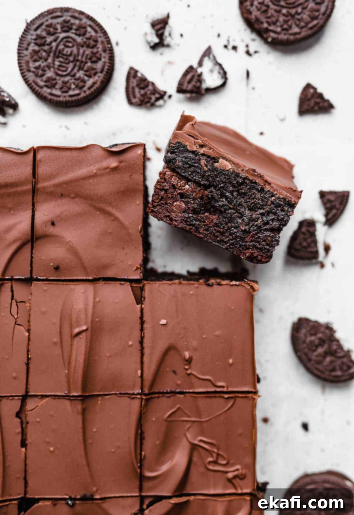 Όρεο Τρούφα Μπράουνις 2 Ένα Brownie Oreo Truffle σε λευκό φόντο με θρυμματισμένα Oreo σκορπισμένα τριγύρω.