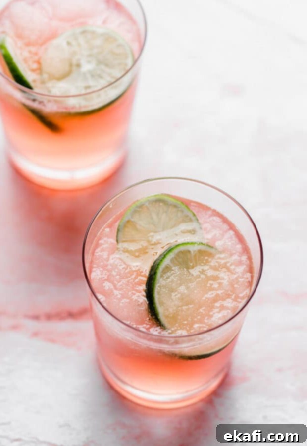 Δύο ποτήρια Limeade Slush Punch με φέτες λάιμ σε κάθε ποτήρι, έτοιμα για απόλαυση.