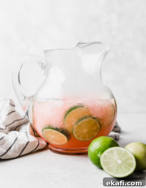 Μια κανάτα γεμάτη Limeade Slush Punch και φέτες λάιμ, έτοιμη να σερβιριστεί.