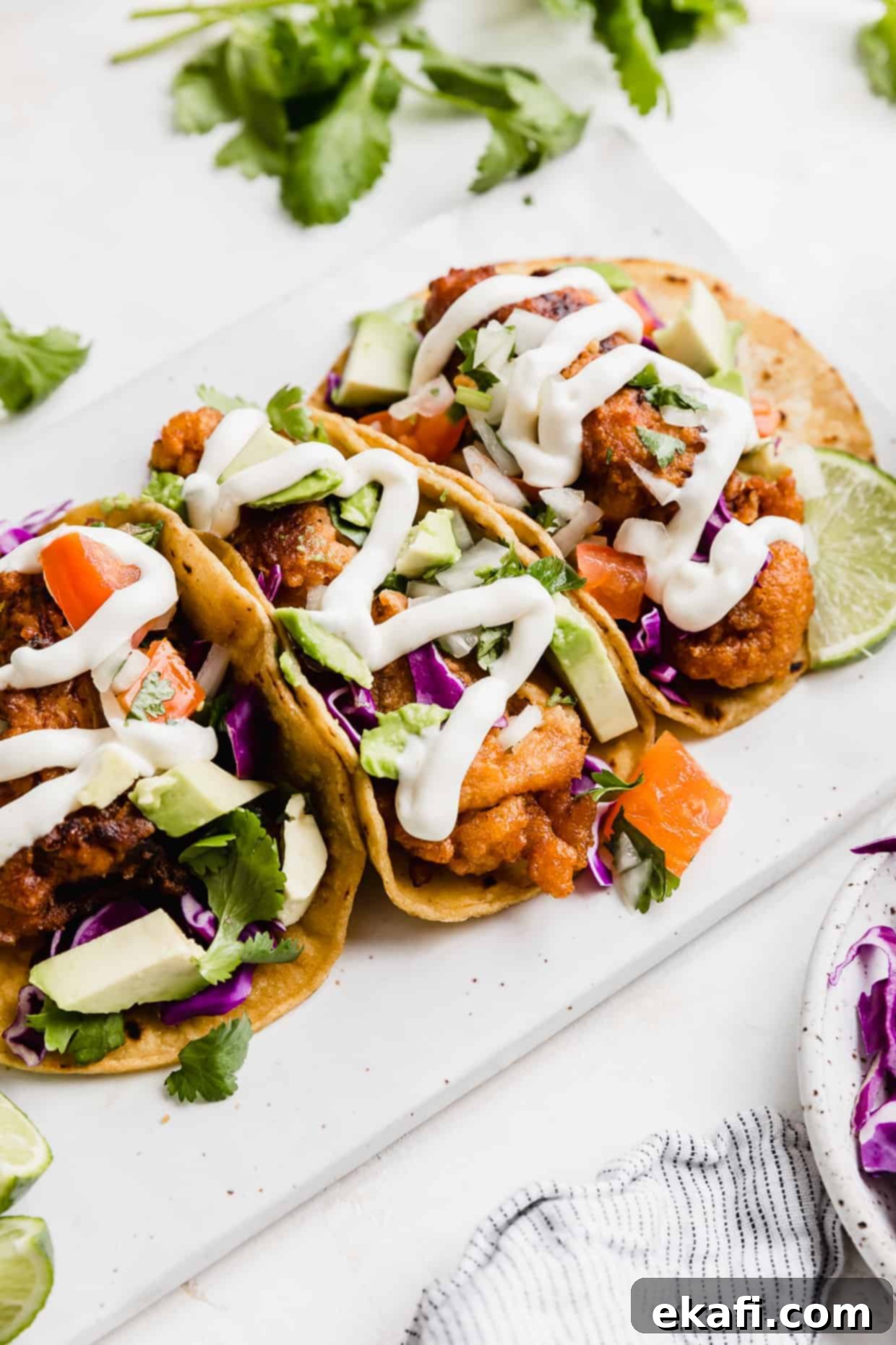 Crispy Fish Taco Bliss 10 Beautifully assembled Baja Fish Tacos on a white plate, topped with white sauce, vibrant pico de gallo, creamy avocado, and crisp cabbage, ready to be enjoyed.