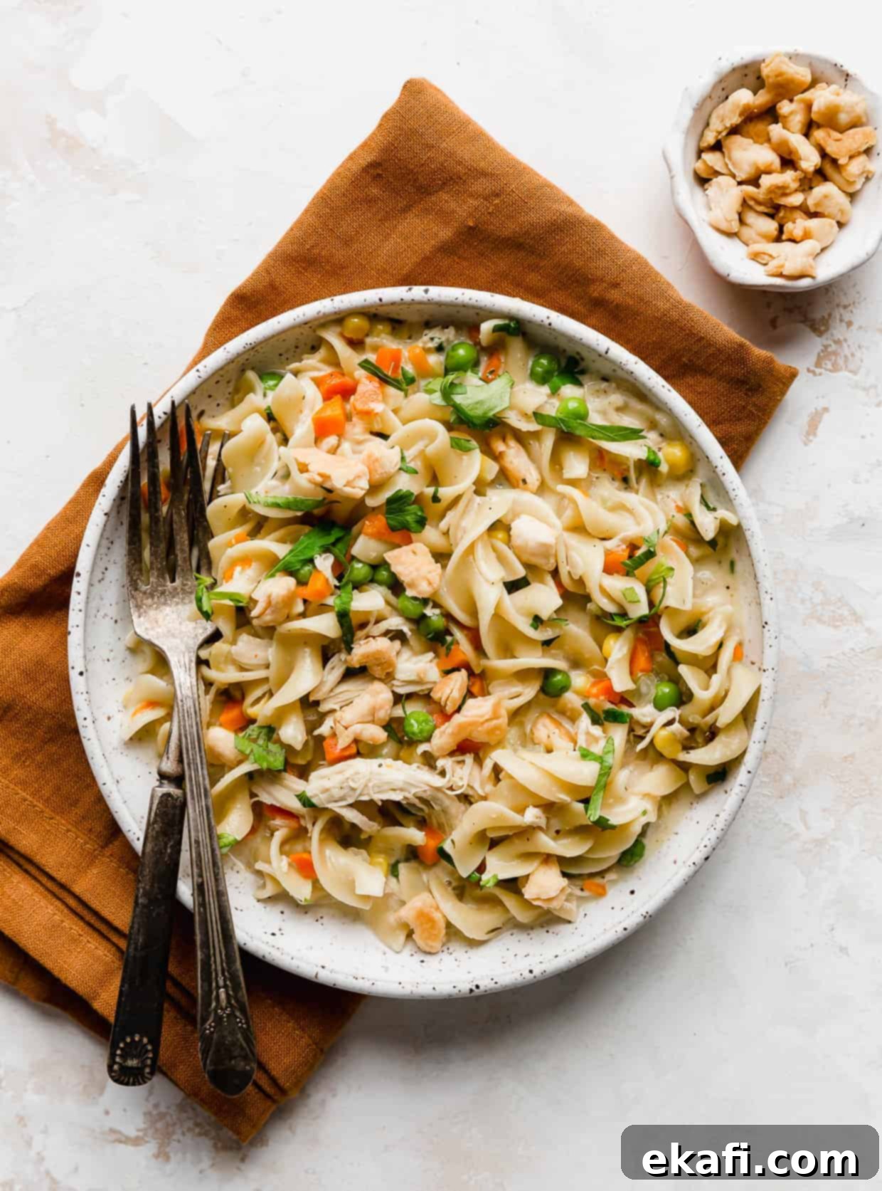 Creamy Chicken Pot Pie Noodles 2 A white plate full of chicken pot pie noodles resting on a burnt orange linen napkin.