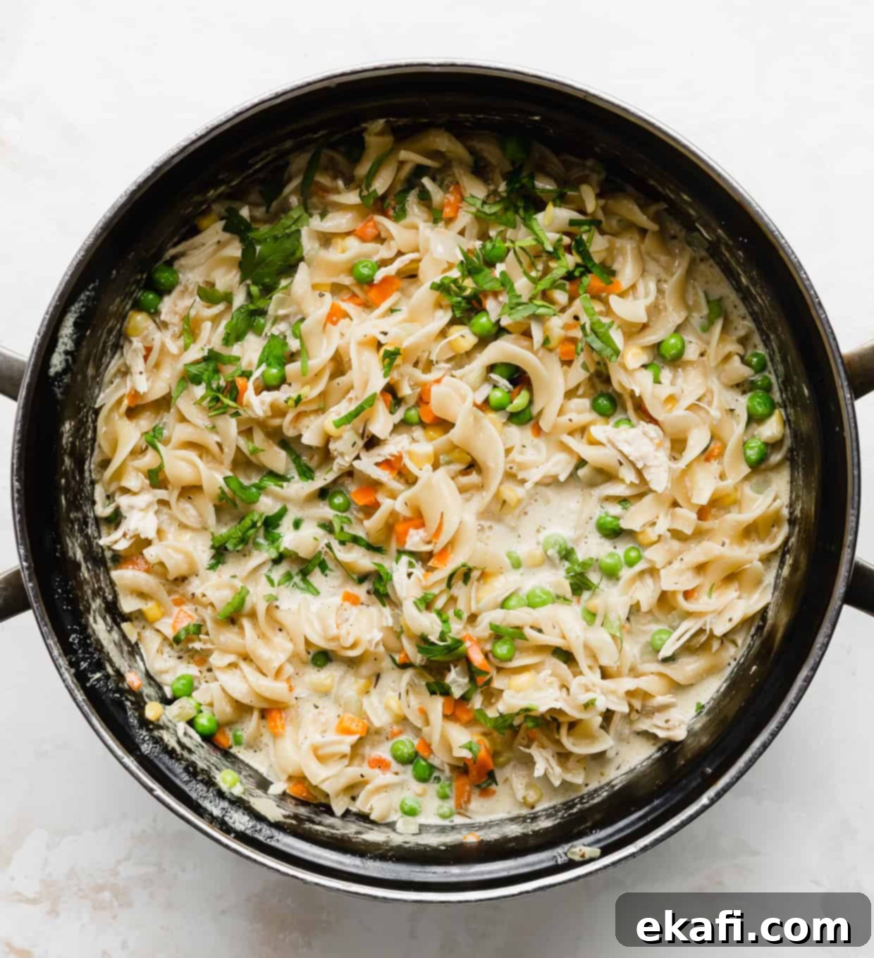 Creamy Chicken Pot Pie Noodles 5 A pot full of egg noodles, diced carrots, and peas.