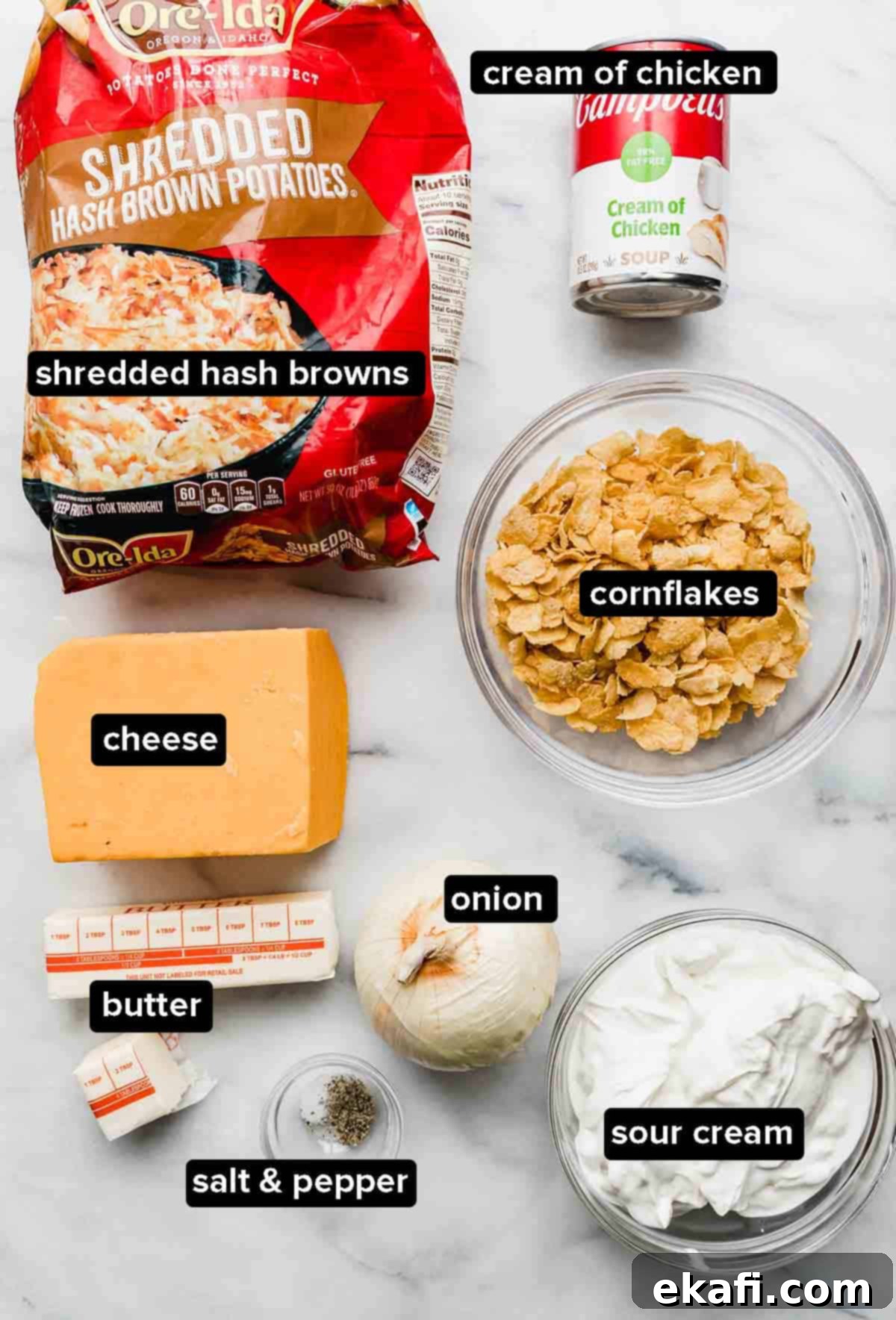 Soul-Soothing Spuds 3 Funeral Potatoes ingredients on a white background: frozen shredded hash browns, cheddar cheese, cornflakes, butter, onion, cream of chicken soup, sour cream, salt, and pepper.