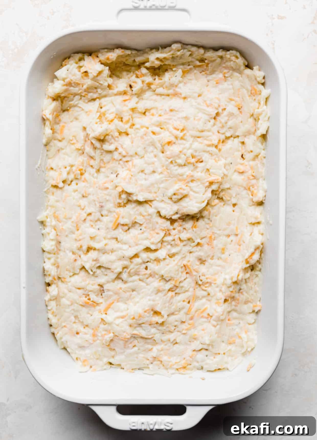 Soul-Soothing Spuds 6 A white casserole dish filled with an even layer of unbaked funeral potatoes against a white background.