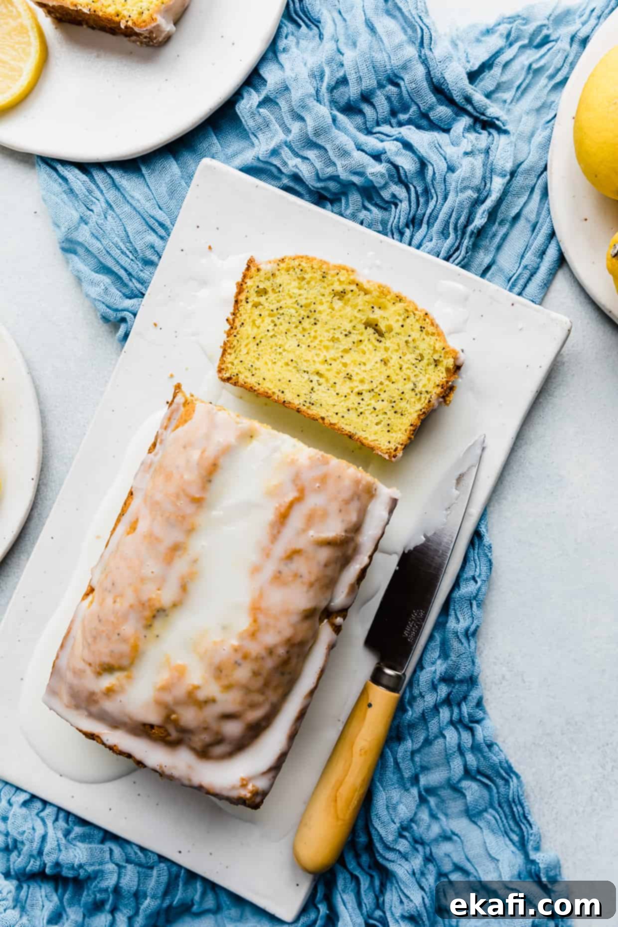 Cake Mix Lemon Poppy Seed Loaf 2 Overhead photo of Lemon Poppy Seed Bread on a white rectangle plate resting on a blue cloth.