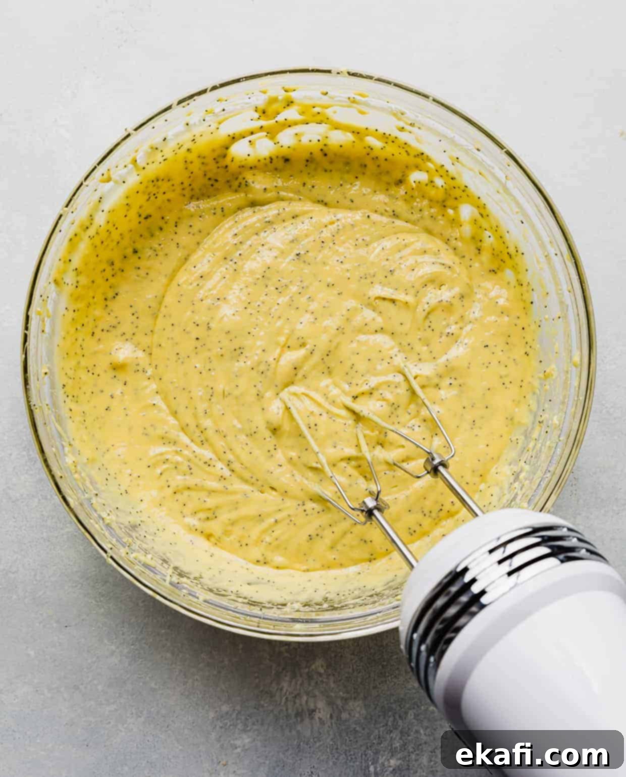 Cake Mix Lemon Poppy Seed Loaf 5 Lemon Poppy Seed Bread batter in a large glass bowl against a white background.