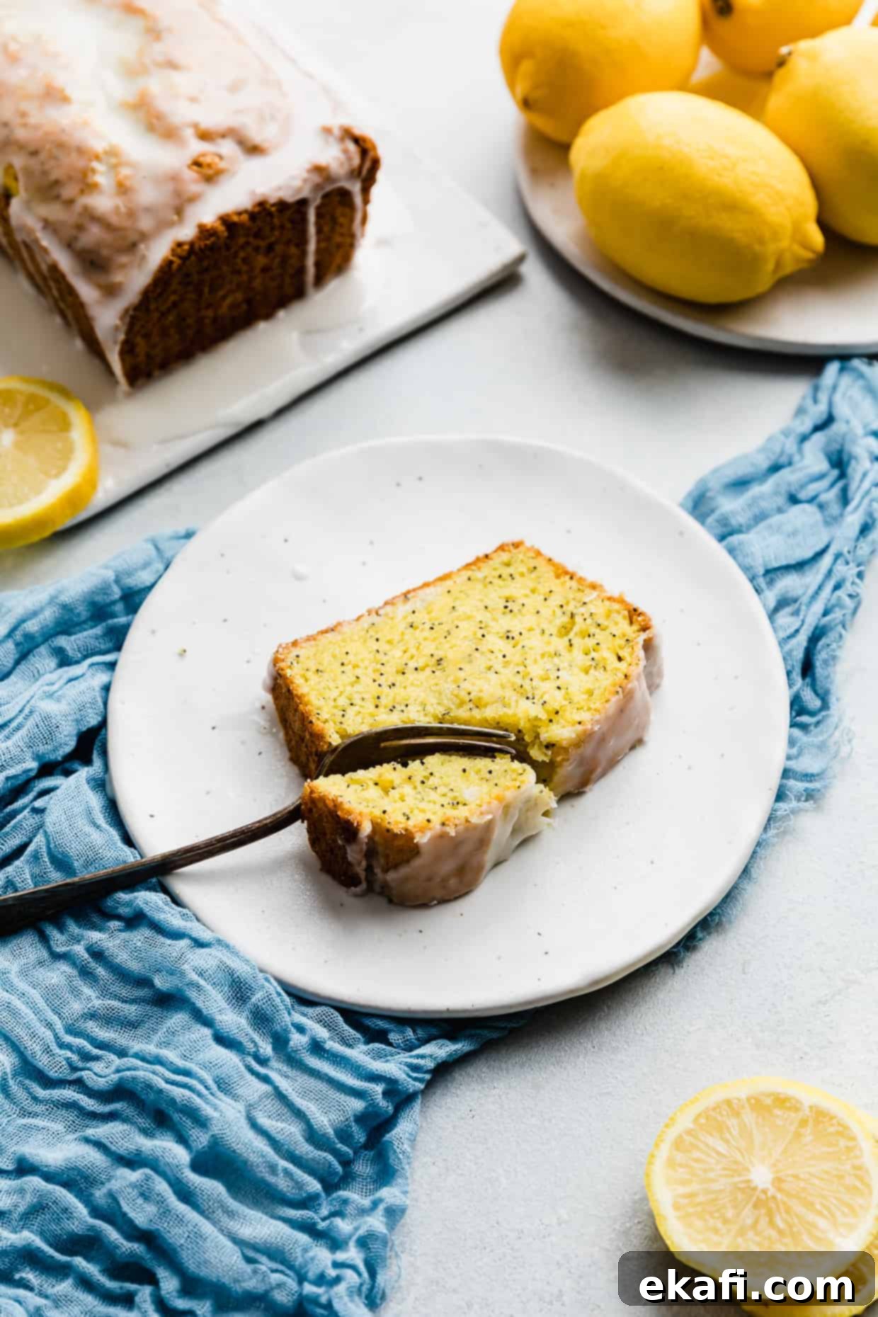 Cake Mix Lemon Poppy Seed Loaf 9 A fork cutting into a slice of lemon poppy seed bread on a white plate.