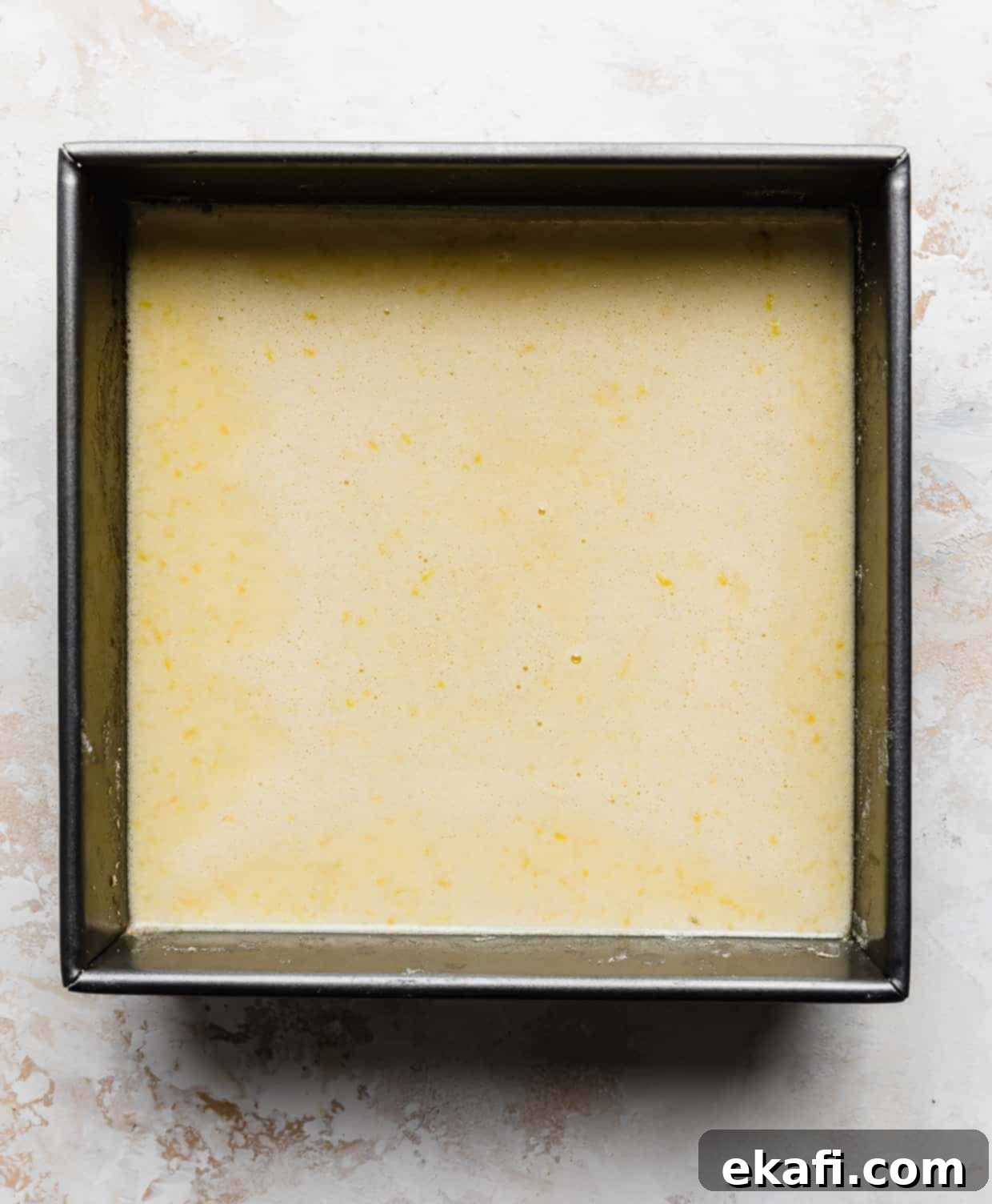 Irresistible Old Fashioned Lemon Squares 6 A square baking pan containing the unbaked vibrant yellow lemon bar filling poured over the crust.