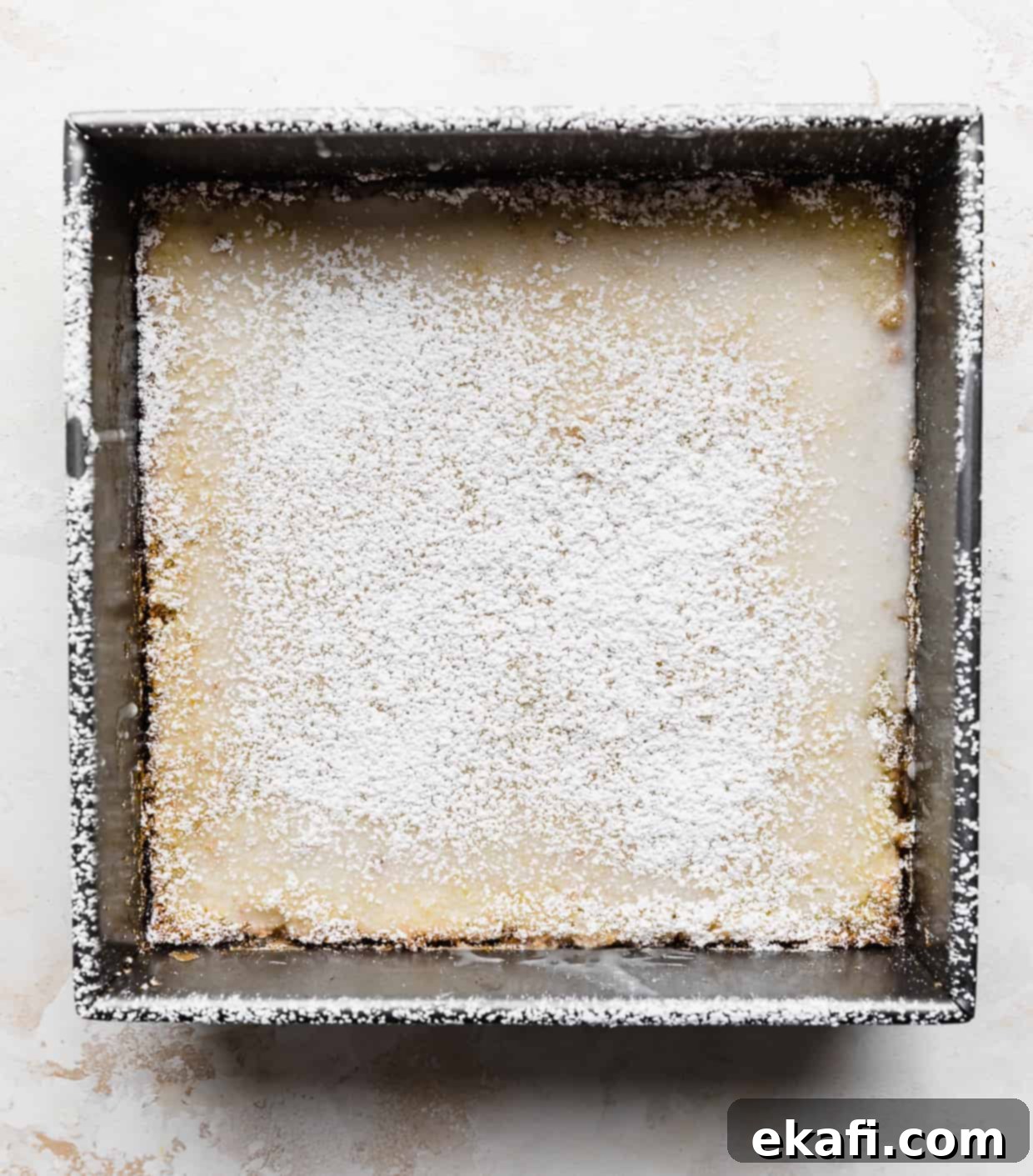 Irresistible Old Fashioned Lemon Squares 9 A square pan of lemon bars, beautifully dusted with powdered sugar, ready for slicing.