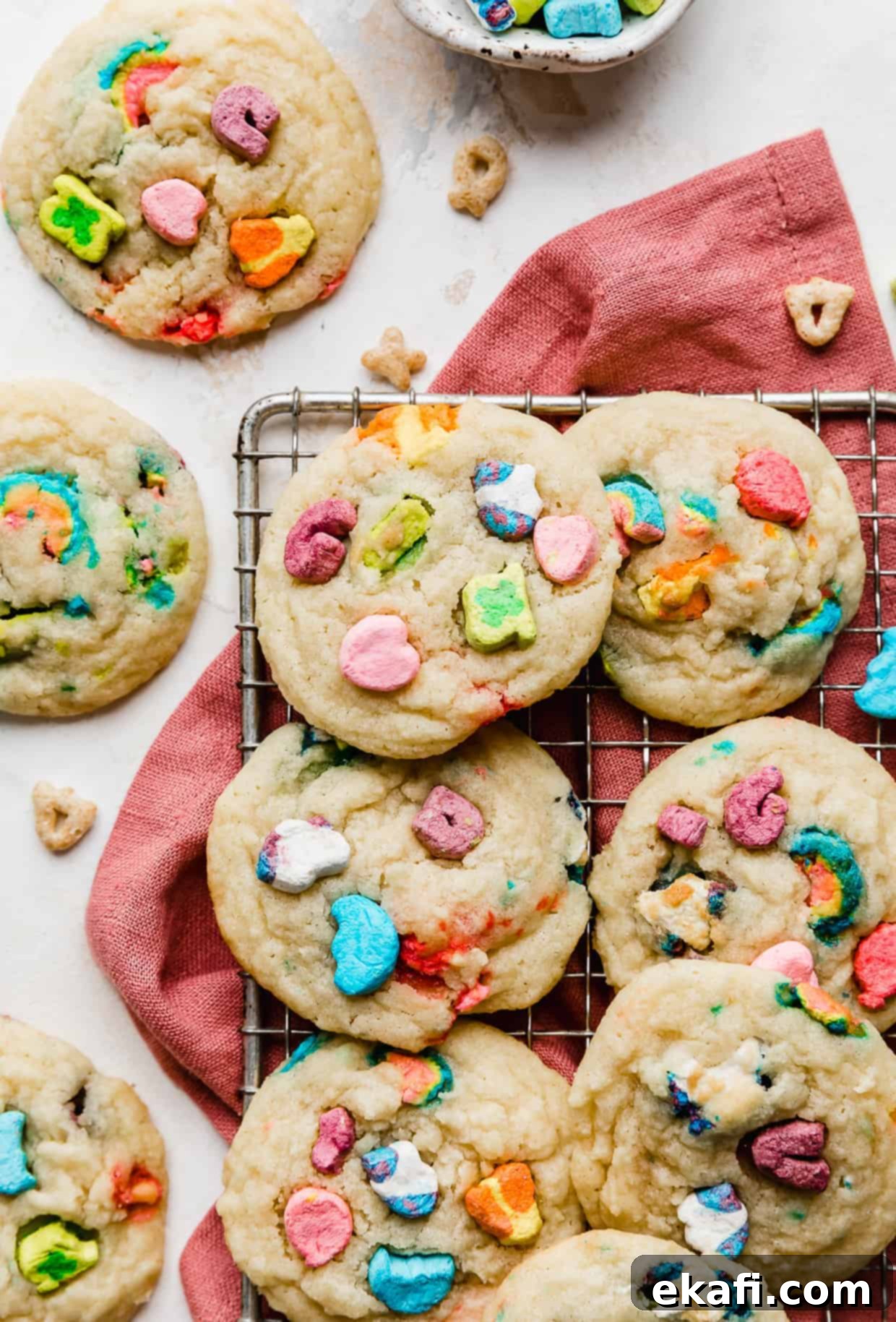 Magic Lucky Charms Cookies 13 Lucky Charms Cookies on a dark pink napkin against a white background, showcasing their vibrant colors.