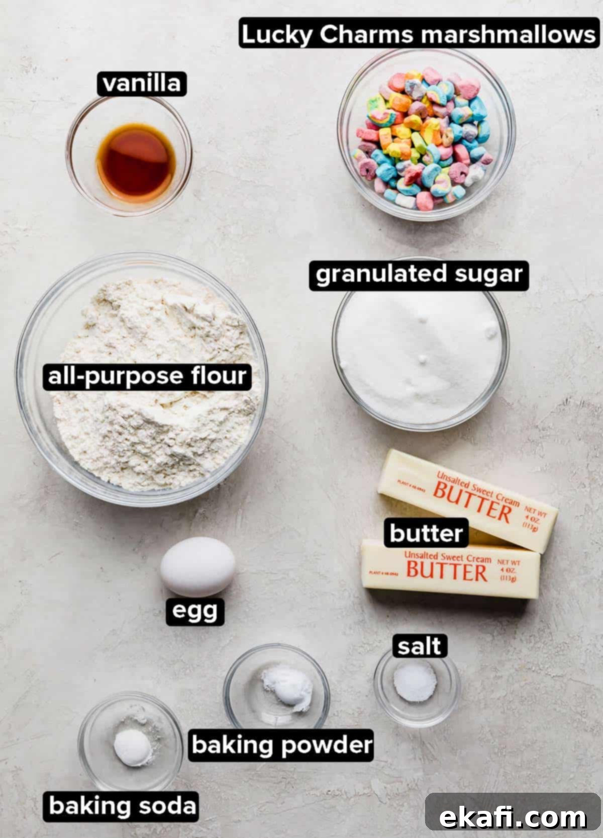 Magic Lucky Charms Cookies 3 Lucky Charms Cookies ingredients in glass bowls on a light grey background, including butter, sugar, flour, and marshmallows.