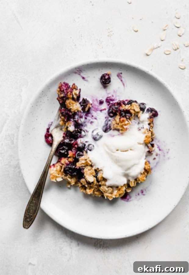 Τραγανό γλυκό μύρτιλο 9 Ένα πιάτο με Blueberry Crisp με παγωτό βανίλια από πάνω.