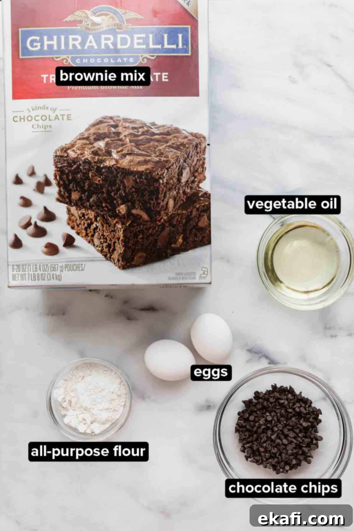 Fudgy Brownie Cookies 3 Ghirardelli brownie mix cookies ingredients laid out on a white background: a box of brownie mix, eggs, flour, vegetable oil, and chocolate chips.