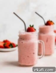 Tropical Strawberry Pineapple Smoothie 9 Two mason jar glasses full of Strawberry Pineapple Smoothie with a fresh strawberry resting on the top of the smoothie.