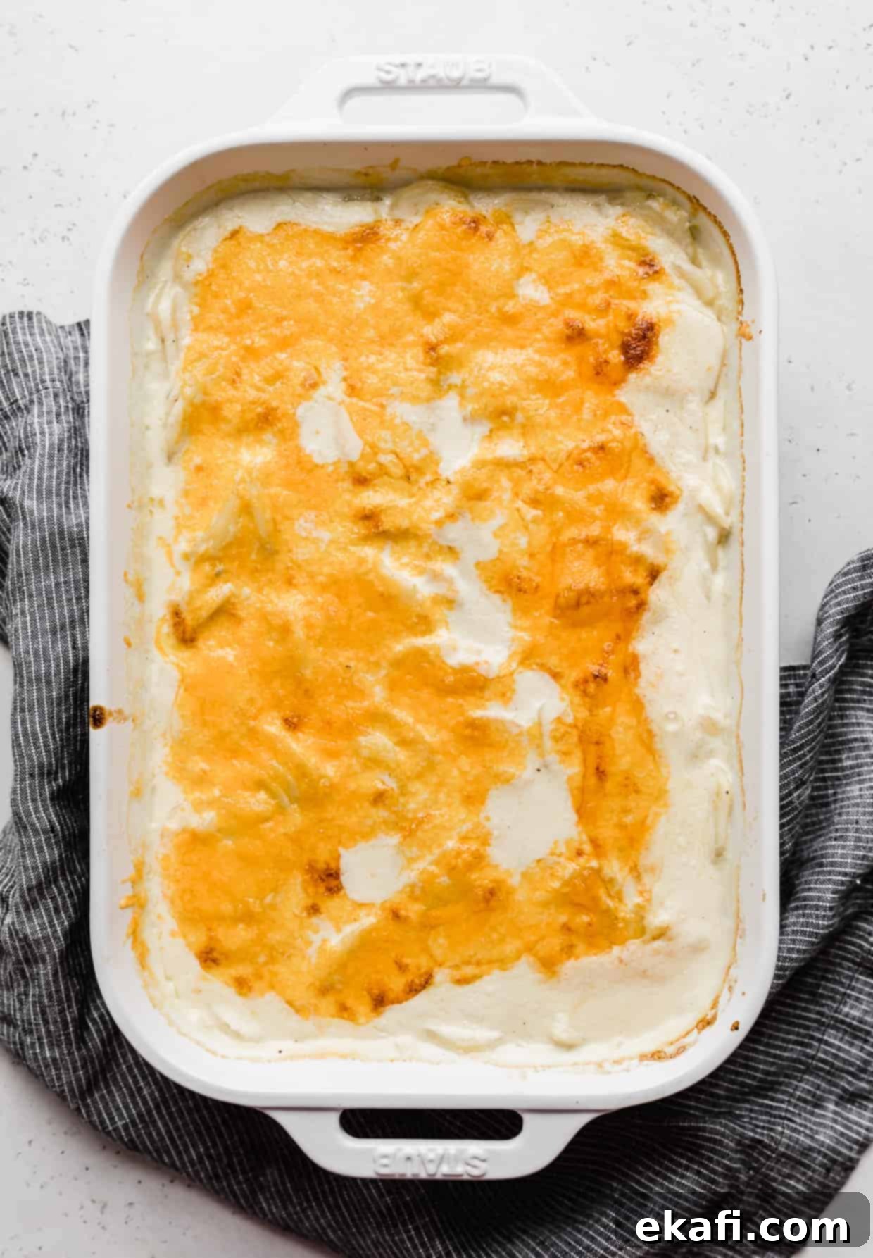 Creamy Gluten-Free Scalloped Potatoes 8 Melted cheddar cheese over thinly sliced potatoes in a creamy sauce against a gray background.