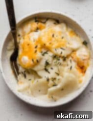 Creamy Gluten-Free Scalloped Potatoes 10 A Creamy Scalloped Potatoes Recipe in a white bowl topped with fresh thyme and cheese.