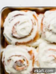 Orange Rolls 13 White frosting covered Orange Rolls on a baking sheet, ready to be served, showing a close-up of the delicious frosting.